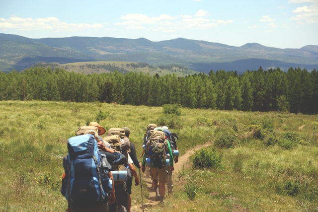 Four backpackers taking hiking advice while walking through the hills.
